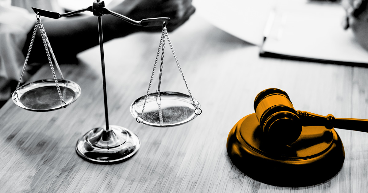 Image of lady justice infront of two out of focus figures